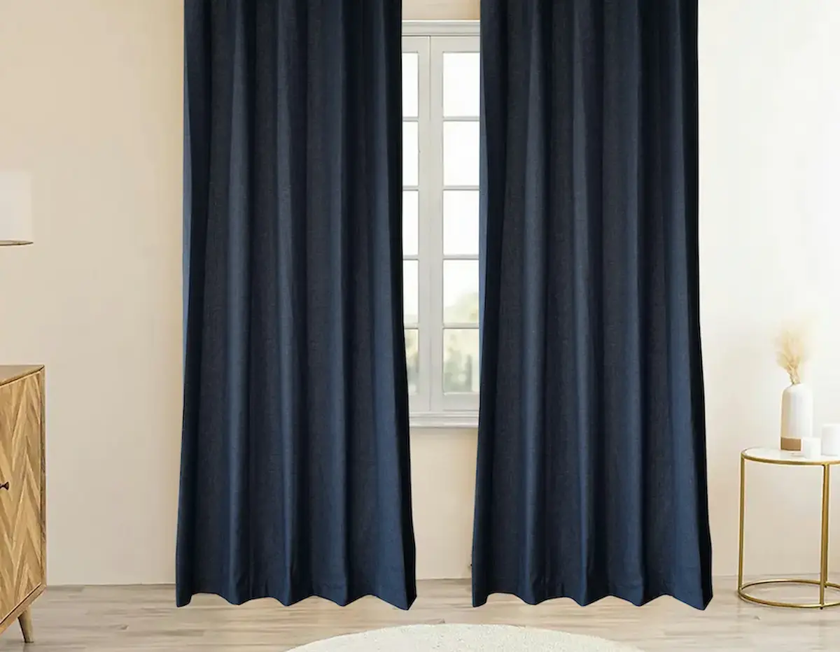 Pair of navy blue thermal insulated blackout curtains in a bright modern UK bedroom